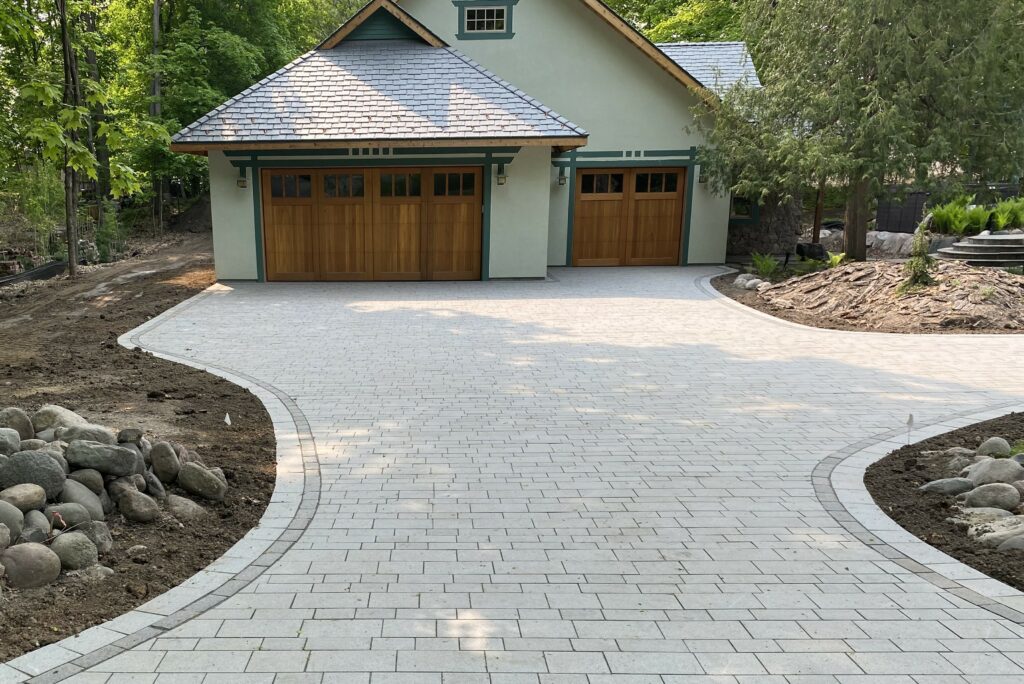 exterior of a home with a paved driveway and custom landscaping - Yellow Brick Road Pavers & Landscapes LLC