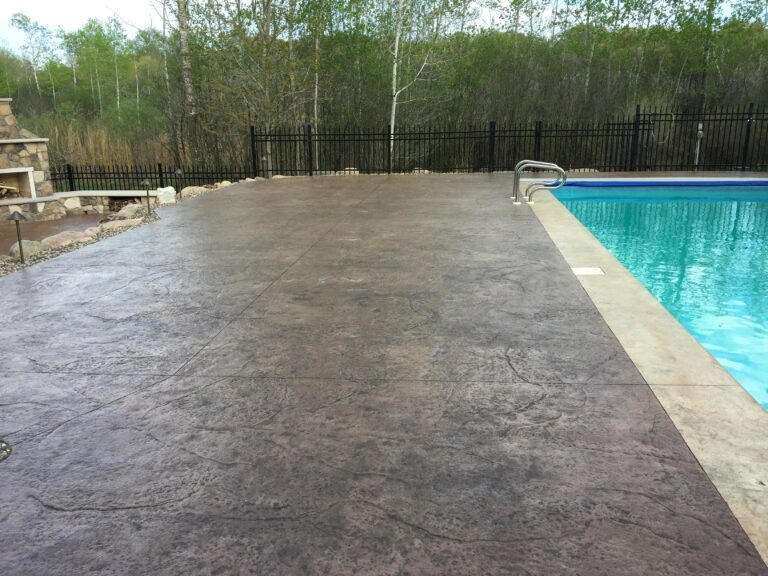 Textured stamped concrete pool deck and smooth concrete coping next to an inground swimming pool - Yellow Brick Road Pavers & Landscapes LLC