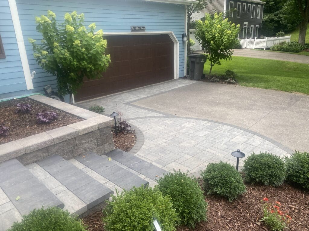 Landscaped home exterior featuring a stone pathway, steps, decorative plants, and a garage with a brown door, enhancing curb appeal.